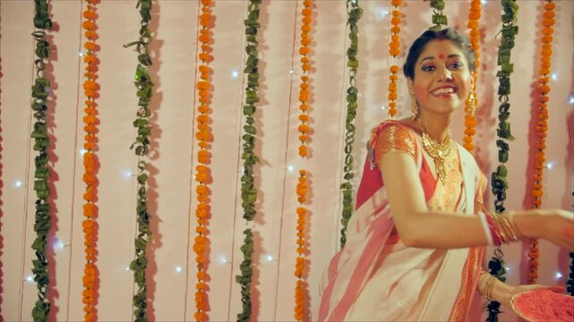 A cheerful Bengali lady playing with Sindur (Sindur Khela) during Durga Puja. A medium shot of a married Bengali woman in a red-white saree playing with vermilion on Vijaya Dashami - A Durga Puja T...