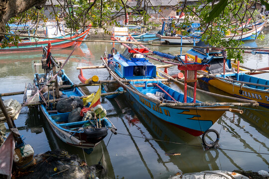 Cilacap, Indonesia - May 15, 2026: Colorful traditional outrigger fishing boats moored together along the waterfront in Cilacap.