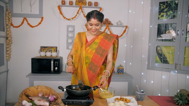 An Indian Bengali wife cooking and presenting her food - festival scene. Medium shot of a traditional married lady making cutlets in her kitchen for her guests during Durga Puja celebration