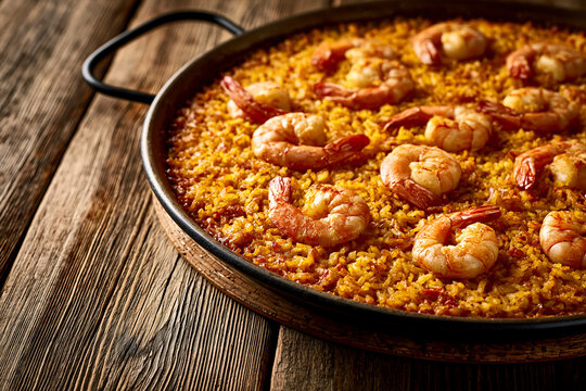 Close-up of shrimp paella in pan on rustic wooden table