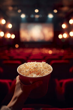 Popcorn in cinema seat with blurred movie screen lights