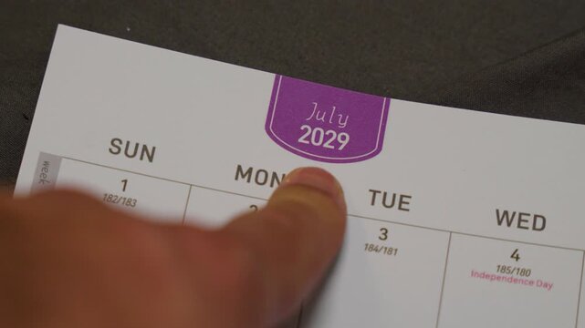 finger pointing at July 2029 planner page close up for scheduling and monthly planning concept