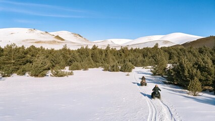Aerial view of snow mobiles traveling across a snowy arctic tundra in the high mountains on a cold winters day.  © pinan