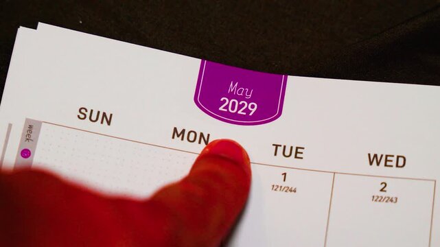 finger pointing at May 2029 planner page close up for scheduling and monthly planning concept