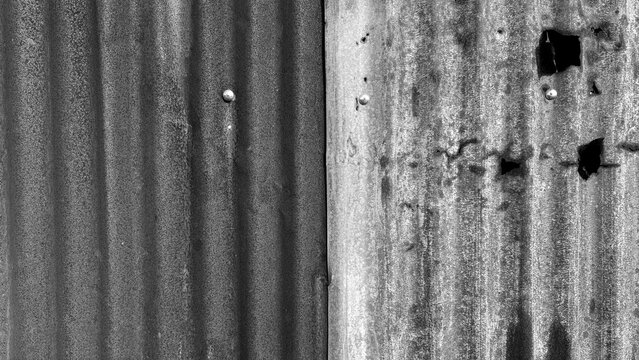 Damaged rusted zinc sheet texture with holes in black and white