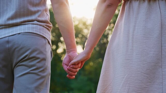 Couple holding hands at sunset in summer setting