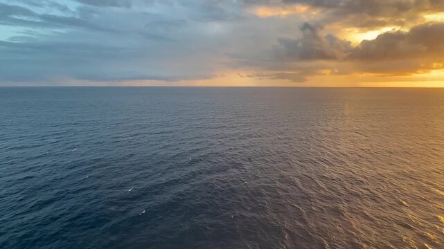 Short cinematic clip of the calm Caribbean Sea during sunset, captured from the upper
deck of a cruise ship near Saint Kitts Island. The glowing sun dips toward the horizon, casting warm golden and or