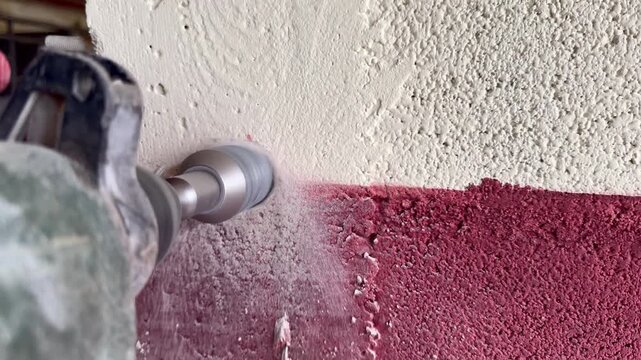 Worker drilling concrete wall on construction site close up