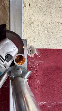 Angle grinder cutting steel pipe with sparks at worksite
