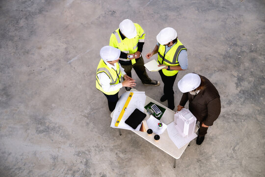 Real estate developers are evaluating construction sites to install solar power systems or utilize natural energy to future green building. High angle top view professional teamwork brainstorming.