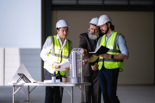 Investor site visit reviewing architectural layout model empty facility, engineers reporting skyscraper construction progress investor site temporary table temporary workspace site.