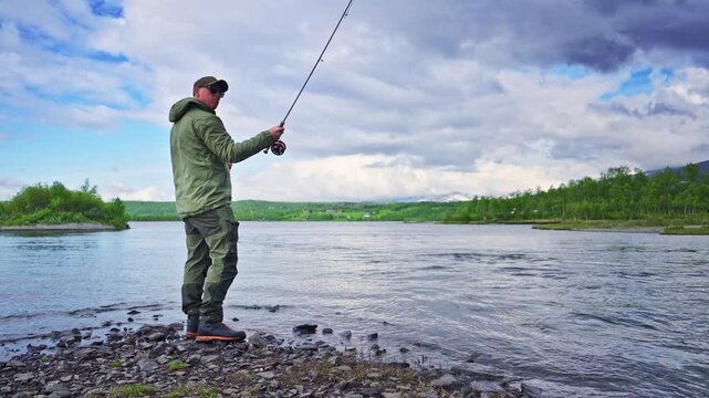 A man is flyfishing after trout in a mountain lake in Stugudal, Norway