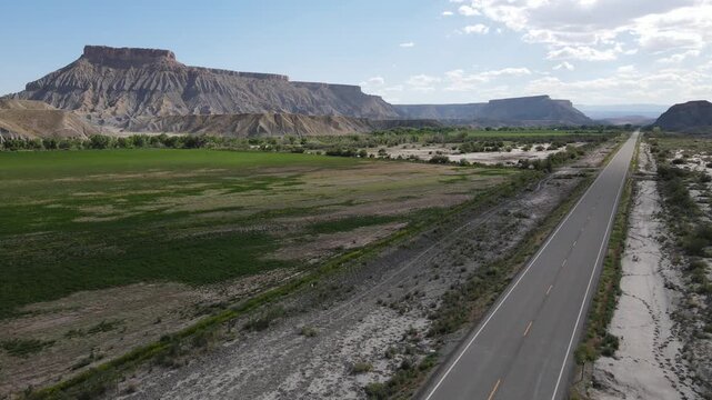 Cinematic 4K drone shot descending for a landing on an empty asphalt road near Factory Butte in Utah. Smooth movement at 60fps, perfect for high-quality slow motion or reverse takeoff effects.