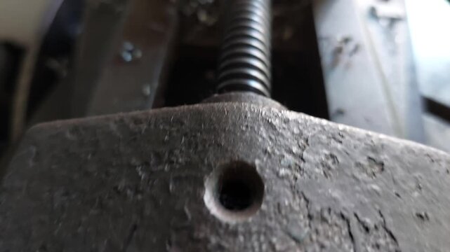 Macro pan shot of a heavy duty metal workshop vise screw thread and handle mechanism