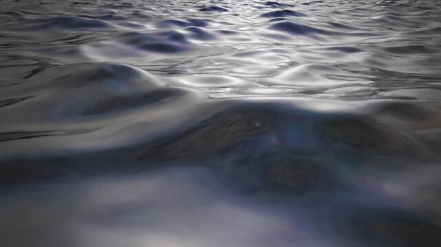Abstract close up of rippling dark liquid surface with light reflections