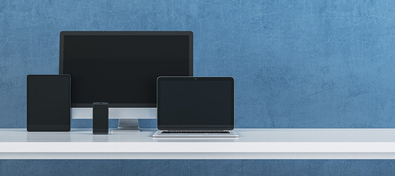 Modern digital device set featuring computer monitor, laptop, tablet and smartphone arranged on clean desk against textured blue background for technology branding. 3D Rendering