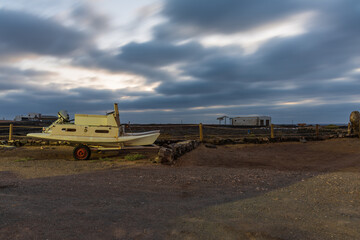Fototapeta premium Small Fishing Boat on Trailer near Salt Museum in Fuerteventura Volcanic Coast Landscape