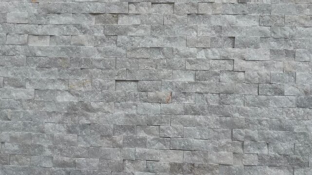 Stone wall texture with uniform gray bricks suitable for use as a seamless background