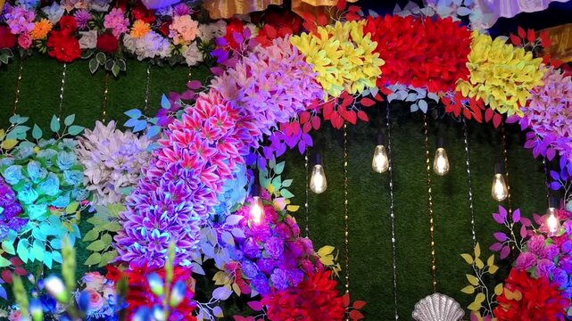 Beautiful wedding decoration featuring colorful artificial and fresh flowers, marigold garlands, floral arches, decorative lights, wedding backdrop elements, and festive stage arrangements.