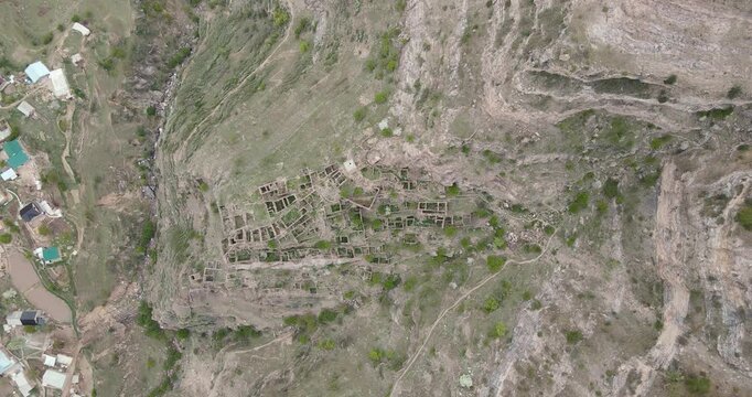 Epic top down aerial zoom out shot of the ancient stone ruins of the abandoned village terraced on mountain cliffs in Kahib, Dagestan
