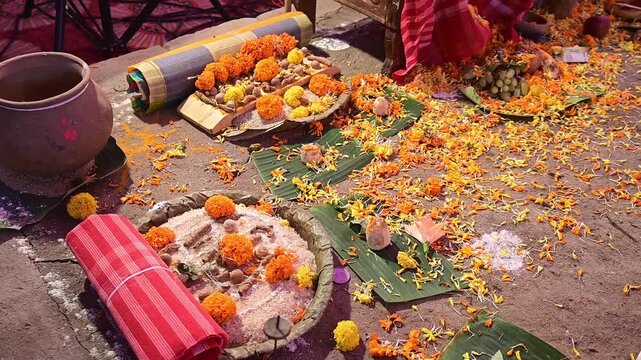 Close-up footage of a traditional Hindu puja setup featuring sacred offerings, marigold flowers, banana leaves, earthen pot, and ritual materials after a havan ceremony