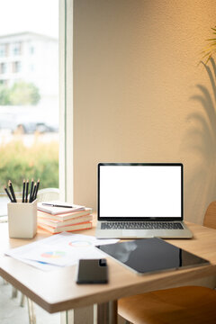 Laptop Mockup with Blank White Screen on Wooden Desk in Bright Modern Workspace by Window