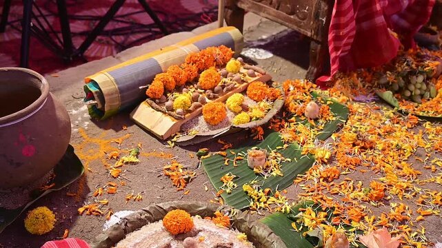 Close-up footage of a traditional Hindu puja setup featuring sacred offerings, marigold flowers, banana leaves, earthen pot, and ritual materials after a havan ceremony