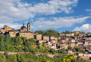 Obraz premium Palazzo Ducale stands majestically in Urbino, Italy, showcasing its medieval architecture against a backdrop of lush greenery and open skies, reflecting the city's storied past.