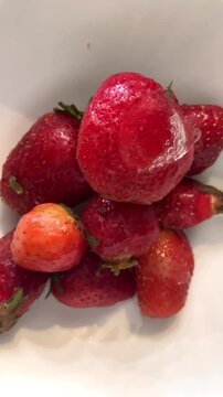 Fresh strawberries sit in a bowl after being washed, ready to be enjoyed or used in recipes at home in the kitchen