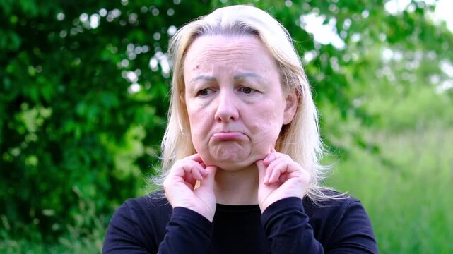 Touching area beneath eyes and along jawline woman reacts with visible frustration and sadness. scene illustrates concerns about aging appearance cosmetic procedures and facial rejuvenation.