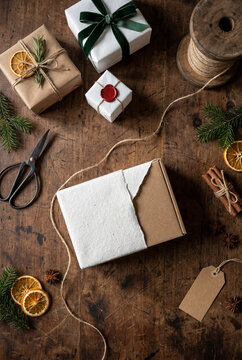 Wrapped Christmas gifts and natural packaging materials on rustic wooden table