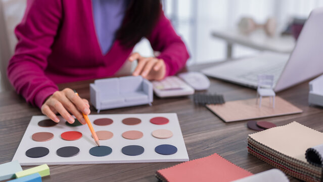 interior designer selecting color palette swatches for furniture upholstery fabric samples creative workspace studio with material chart tools laptop desk