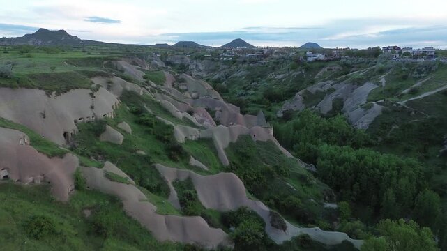 Smooth 4K drone footage over Pigeon Valley, Cappadocia, revealing volcanic rock formations, lush vegetation, and ancient dovecotes carved into tuff rock &mdash; raw, ungraded aerial footage