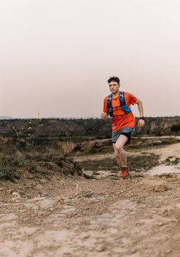 Male ultra runner training on mountain trail at sunset
