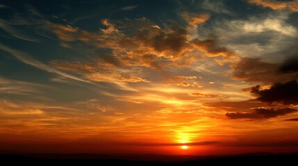Fototapeta premium A warm summer evening sky with the sun dipping below the horizon, creating a golden glow.