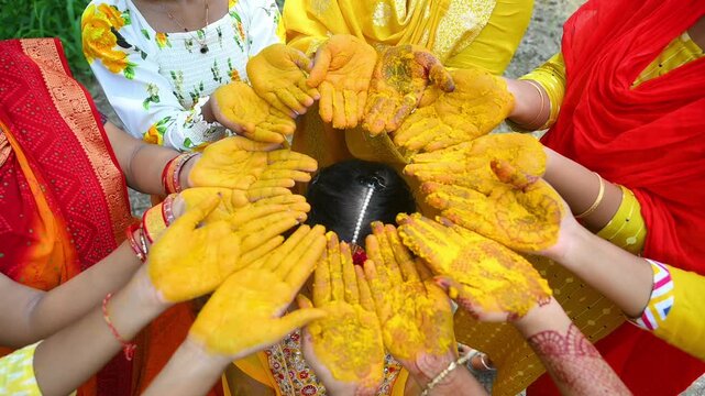 Indian Haldi Ceremony with Bride and Family Applying Turmeric Paste During Traditional Pre Wedding Ritual. Featuring colorful attire, henna-decorated hands, turmeric-covered palms