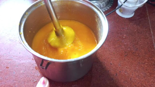 Blending Fresh Mango Pulp with Hand Blender in Kitchen Countertop