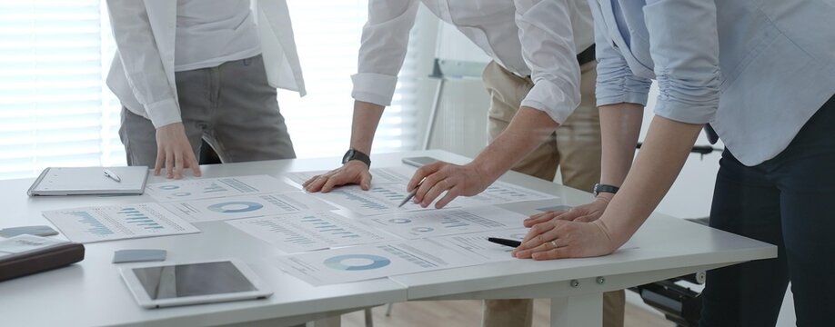 Business professionals collaborating around a modern office table, reviewing charts and reports, brainstorming strategy and data driven decisions to drive growth and team performance