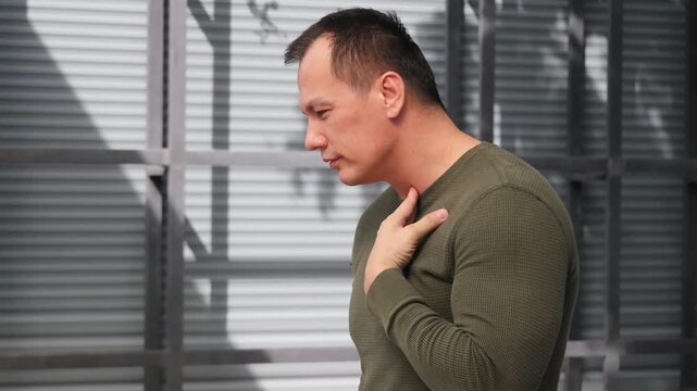 Middle aged Asian man coughing, having sore throat and catching a cold or flu, man suffering from stuffy throat with phlegm