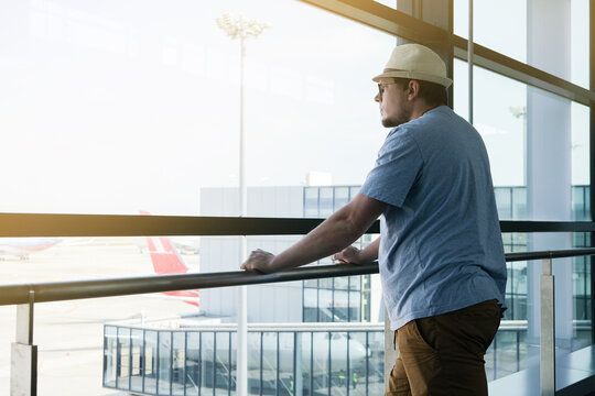 Young man standing by the window while waiting for flight