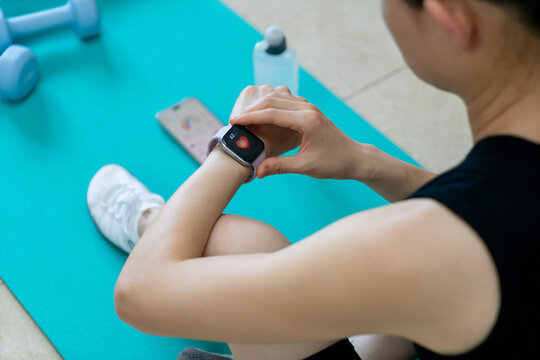Woman checking fitness tracker heart rate during home workout