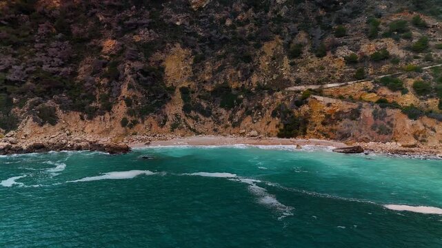 Aerial drone flight over ocean toward Playa de Ambolo, Cap de la Nau, Spain