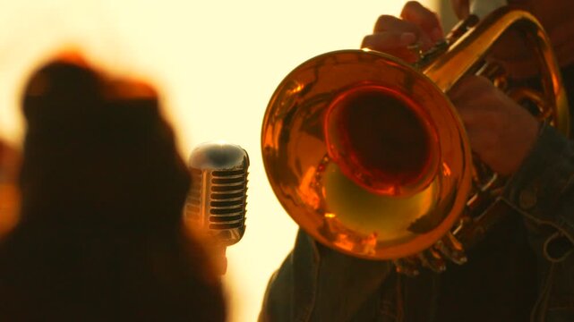 Trumpet musician performance musical artist playing brass instrument next to vintage microphone during sunset live concert session