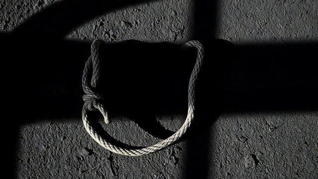A broken rope end on the ground with dramatic shadows.