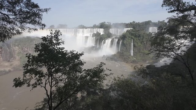 Zoom out from distant waterfall framed by tropical vegetation footage