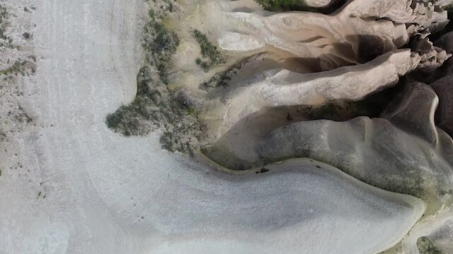 4K drone bird's eye view over Red Valley, Cappadocia, revealing rounded volcanic terrain bathed in warm afternoon light. Raw ungraded footage highlighting the ancient eroded landscape's natural textur