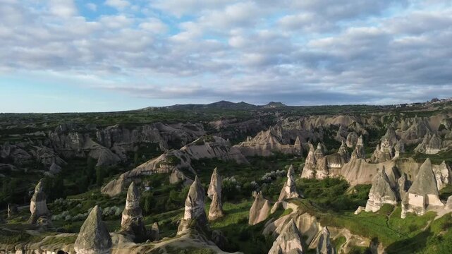 4K drone footage glides over Pigeon Valley at sunrise, revealing cliff faces dotted with hand-carved dovecotes in warm golden light. Raw, unedited aerial footage of this iconic Cappadocia landmark.