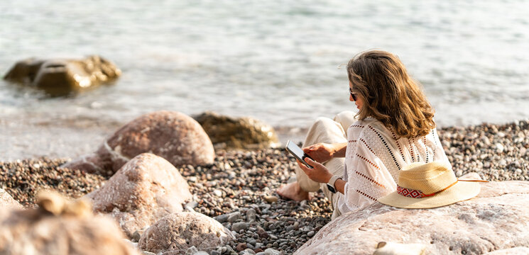 Woman using smartphone on the sea coast at summer