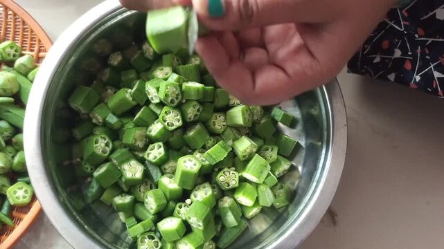 Indian Woman Hands Cutting Fresh Green Okra or Bhindi with a Knife, Close-up