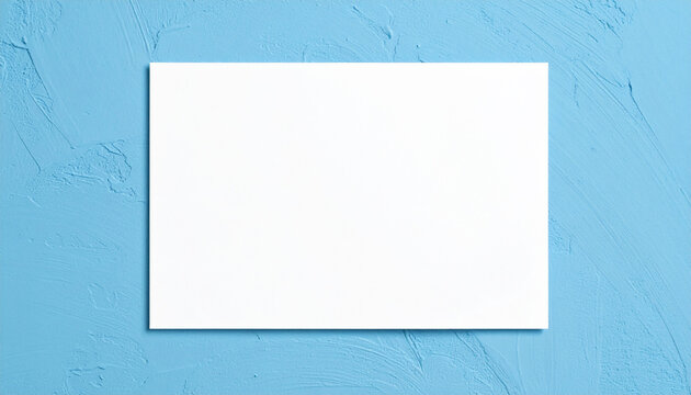 Blank rectangular white poster on blue plaster backdrop, mock-up for design presentation or creative portfolio, soft natural lighting. Close-up.